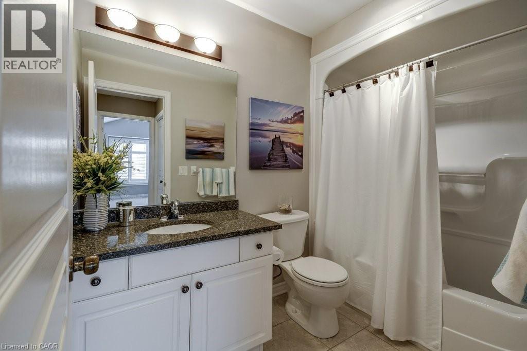 Bathroom featuring a white vanity with paneling, dark speckled countertop, and undermount sink - 605 Welland Avenue Unit# 21, St. Catharines, ON - Indoor Photo Showing Bathroom