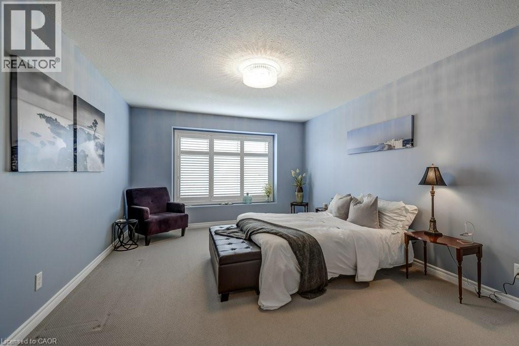 Spacious room with plush carpeting, a large window featuring white plantation shutters, and a contemporary ceiling light fixture - 605 Welland Avenue Unit# 21, St. Catharines, ON - Indoor Photo Showing Bedroom