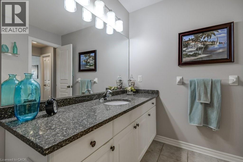 Vanity with stone countertop, integrated sink, and white cabinetry - 605 Welland Avenue Unit# 21, St. Catharines, ON - Indoor Photo Showing Bathroom