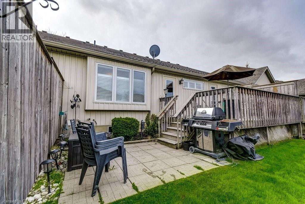 Rear exterior featuring a wood deck, paved patio, and a manicured lawn - 605 Welland Avenue Unit# 21, St. Catharines, ON - Outdoor With Deck Patio Veranda With Exterior