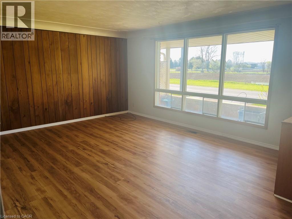 Spacious interior with extensive wood-finish flooring, a prominent wood-paneled accent wall, and a large multi-pane window - 157 Schweitzer Street, Kitchener, ON - Indoor Photo Showing Other Room