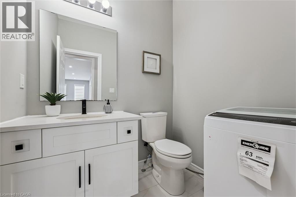Bathroom featuring a white vanity with a light-toned countertop, a rectangular mirror, a chrome light fixture with three bulbs, a single-handle matte black faucet, and light gray wall paint - 628 Florencedale Crescent, Kitchener, ON