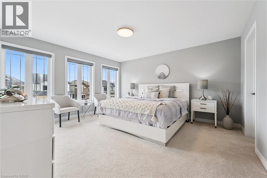 Light-filled room featuring three large windows with roller shades, neutral carpeting, and light gray wall paint - 628 Florencedale Crescent, Kitchener, ON