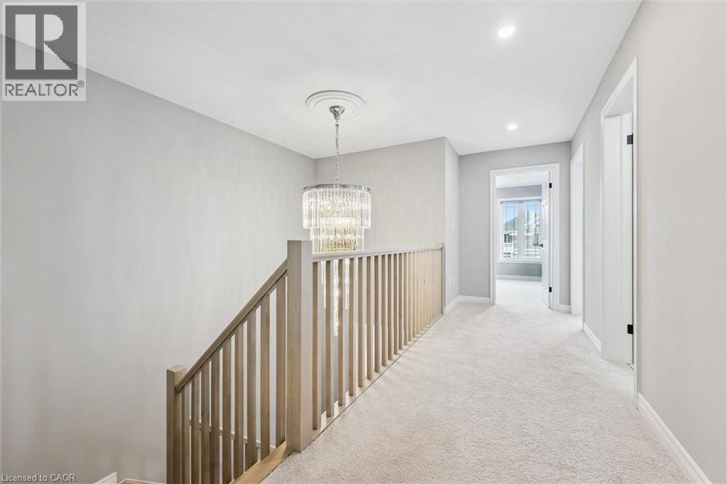 Upper-level hallway featuring a contemporary chandelier with ceiling medallion, light-toned wood banister, neutral carpeting, and recessed lighting - 628 Florencedale Crescent, Kitchener, ON