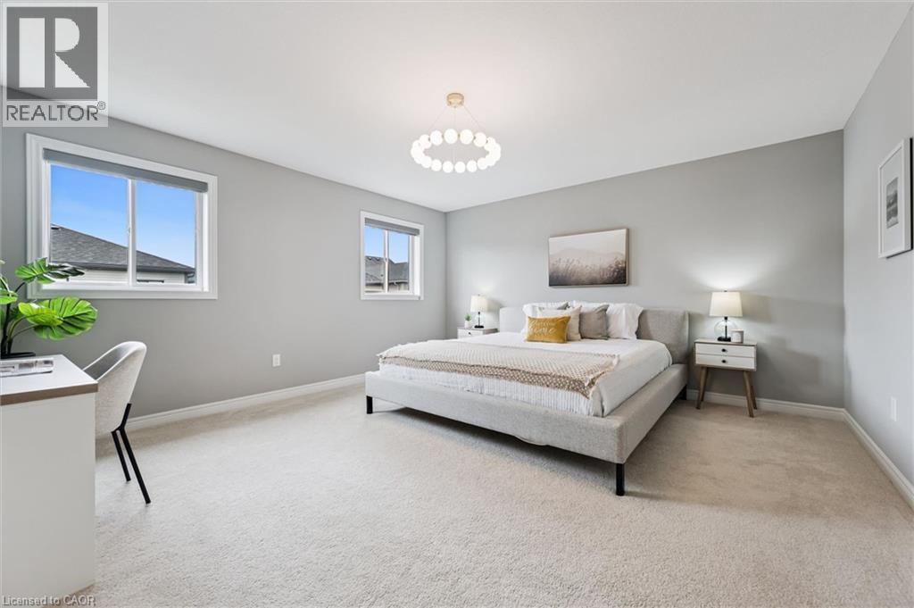 Spacious room featuring light gray walls, plush carpet flooring, two windows with blinds, a modern ceiling light fixture, and white baseboards - 628 Florencedale Crescent, Kitchener, ON