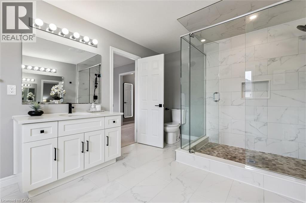 Spacious bathroom featuring a frameless glass shower enclosure with white marble-look tile, a built-in shower niche, and a stone mosaic shower floor - 628 Florencedale Crescent, Kitchener, ON