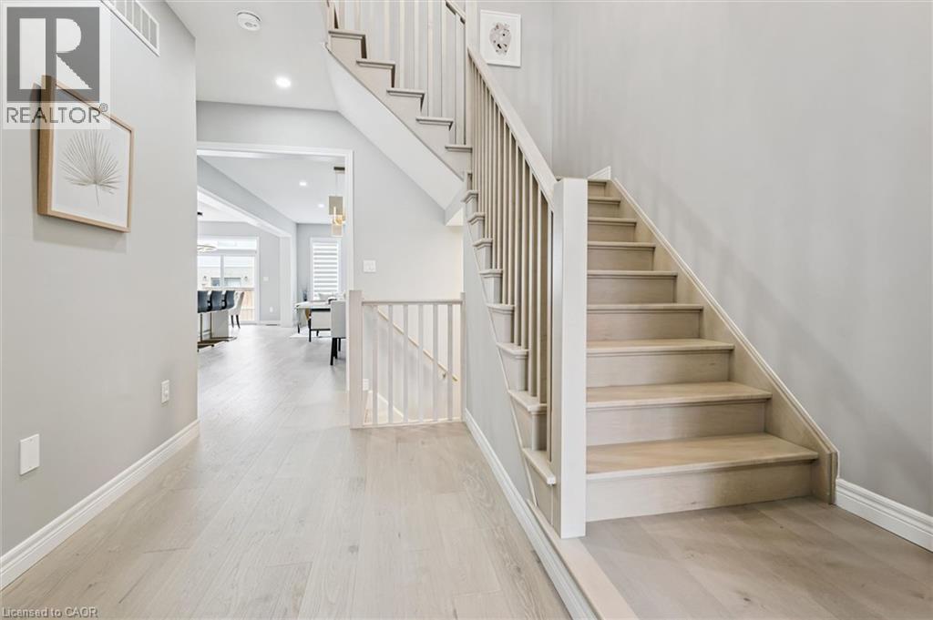 Light wood-finish flooring extending through the hallway and staircase - 628 Florencedale Crescent, Kitchener, ON