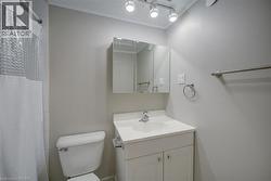 Bathroom featuring a white vanity with integrated sink, coordinating toilet, and track lighting - 