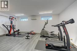 Dedicated fitness room featuring light wood-finish flooring, white walls, and built-in flush lighting - 