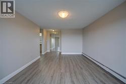 Spacious room with wood-finish flooring, light gray wall paint, and white baseboards - 