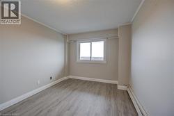 Room featuring light gray walls, wood-finish flooring, white trim, and a window with white framing - 