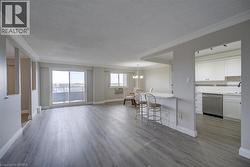 Spacious open-concept living area featuring wood-finish flooring, neutral wall tones, and crown molding - 