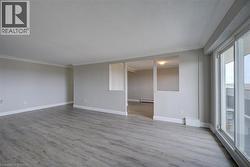 Spacious open-concept living area featuring wood-finish flooring, neutral wall tones, and crown molding - 