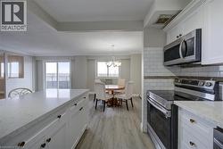 Kitchen featuring white cabinetry, light-toned countertops, and a subway tile backsplash - 
