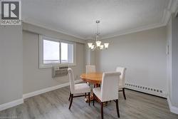 Dining area featuring a window-mounted air conditioning unit, baseboard heating, wood-finish flooring, and crown molding - 