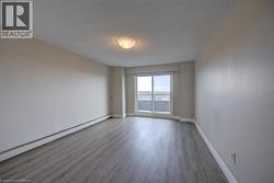 Spacious room featuring wood-finish flooring, light neutral wall paint, and a sliding glass door providing access to an exterior area - 