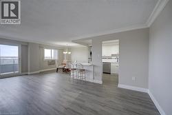 Open-concept living area featuring wood-finish flooring, a sliding glass door to a balcony, and a breakfast bar - 