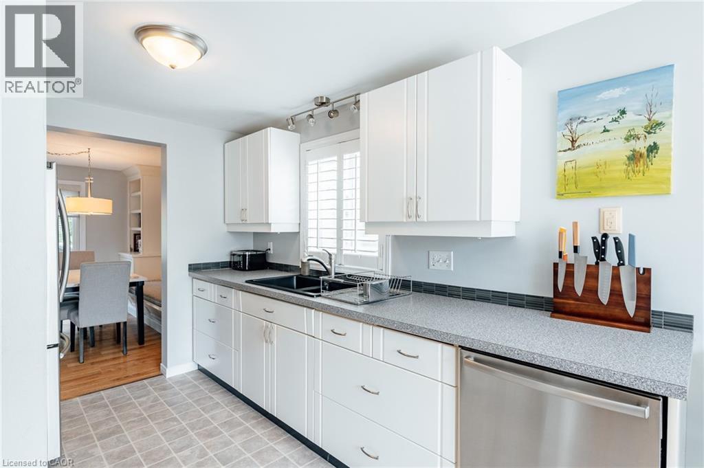 Kitchen featuring white cabinetry, a dark speckled countertop, and a tiled backsplash - 560 Penny Lane, Waterloo, ON