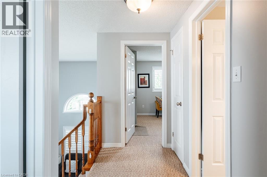 Upper-level hallway featuring textured carpet flooring and light gray painted walls - 560 Penny Lane, Waterloo, ON