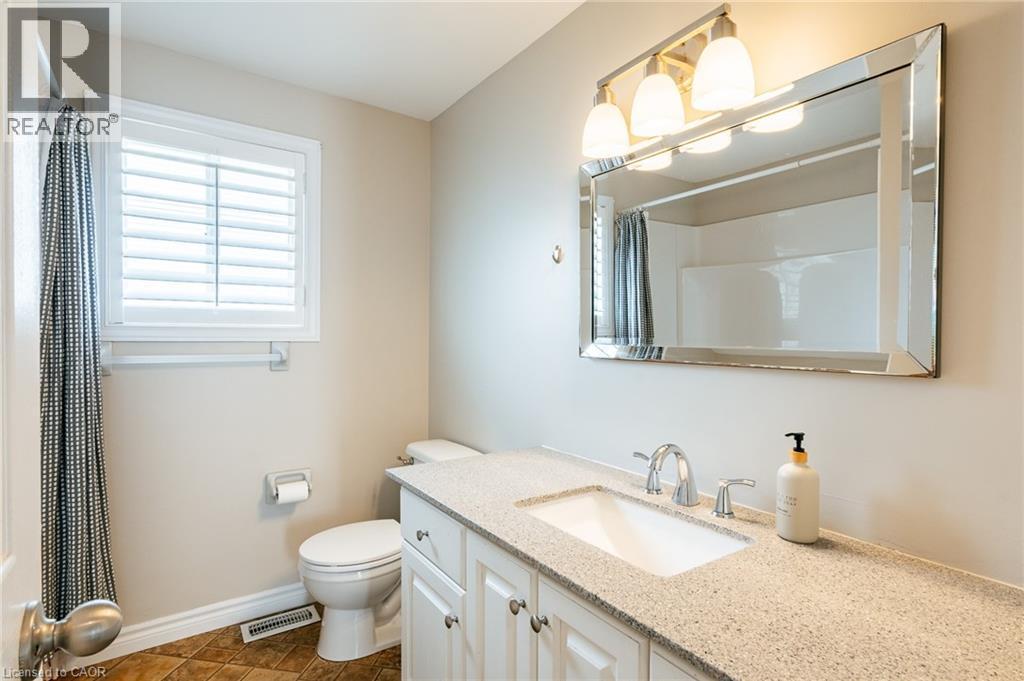 Bathroom vanity featuring a speckled countertop, undermount sink, and chrome faucet - 560 Penny Lane, Waterloo, ON