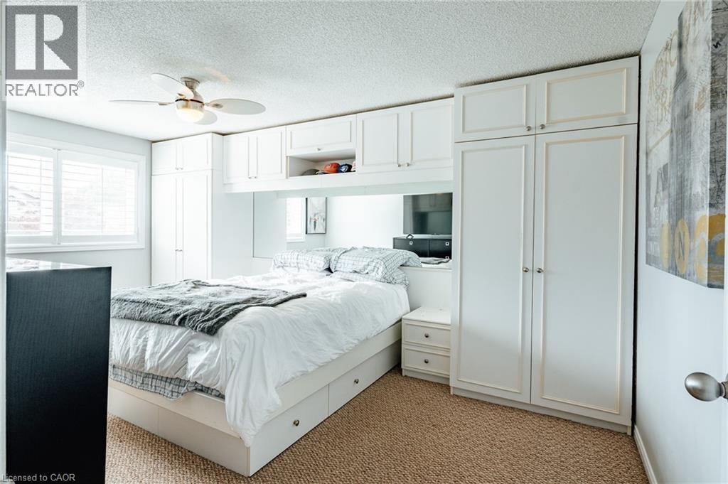 Integrated white cabinetry surrounding the bed frame, featuring multiple storage options - 560 Penny Lane, Waterloo, ON