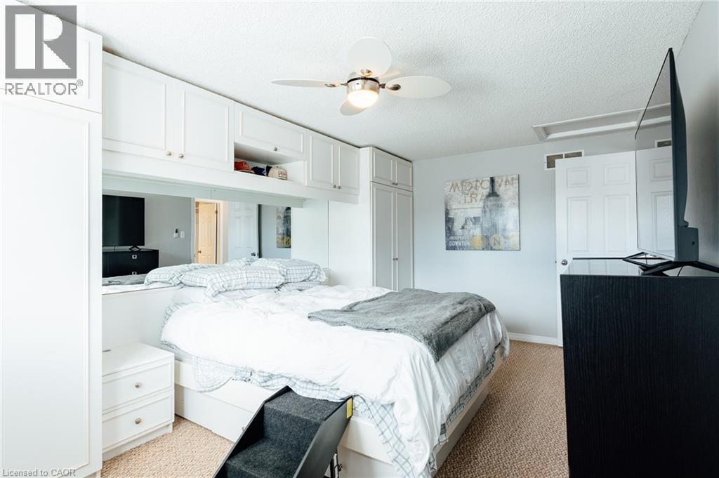 Integrated custom white cabinetry system with an overhead storage bank and built-in bedside tables - 560 Penny Lane, Waterloo, ON