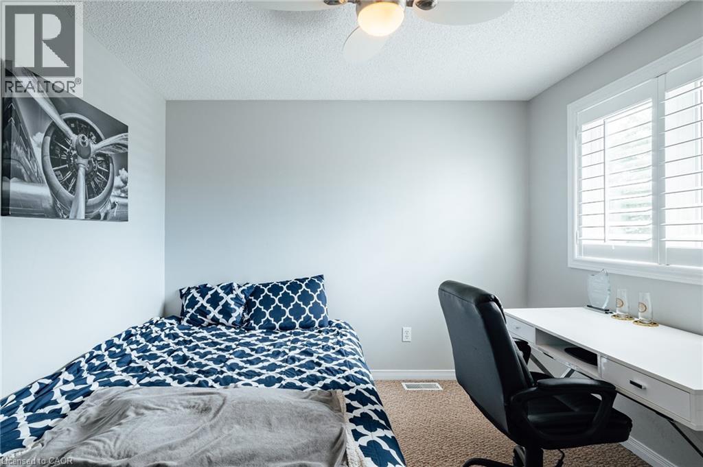 Light-filled room featuring a built-in window with white plantation shutters, a ceiling fan with integrated lighting, and carpet flooring - 560 Penny Lane, Waterloo, ON