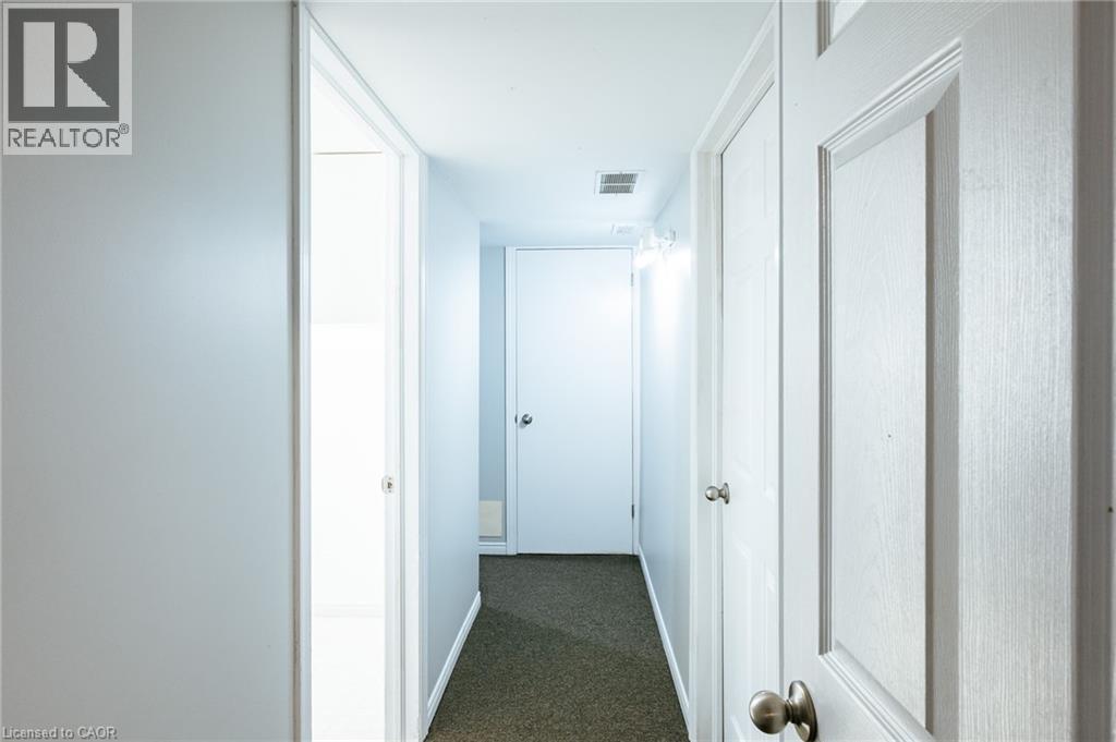 Hallway featuring light gray walls, dark carpet flooring, and white paneled doors with brushed nickel hardware - 560 Penny Lane, Waterloo, ON