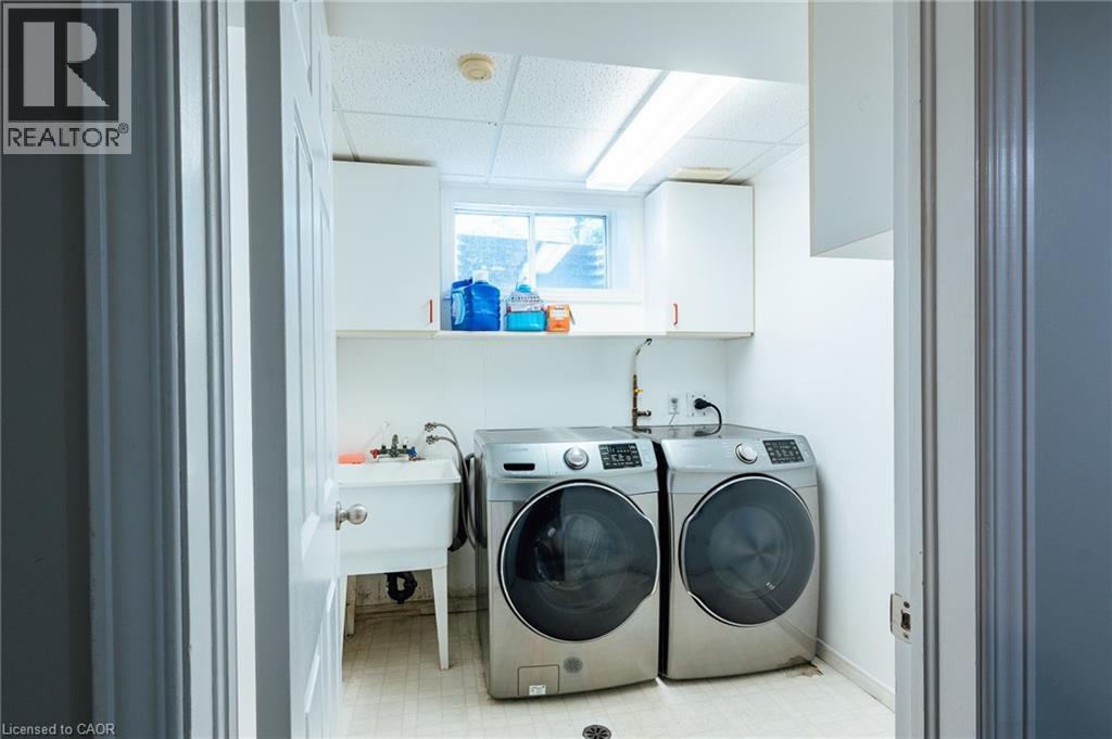 Dedicated laundry room featuring a utility sink, upper cabinetry, and a window - 560 Penny Lane, Waterloo, ON