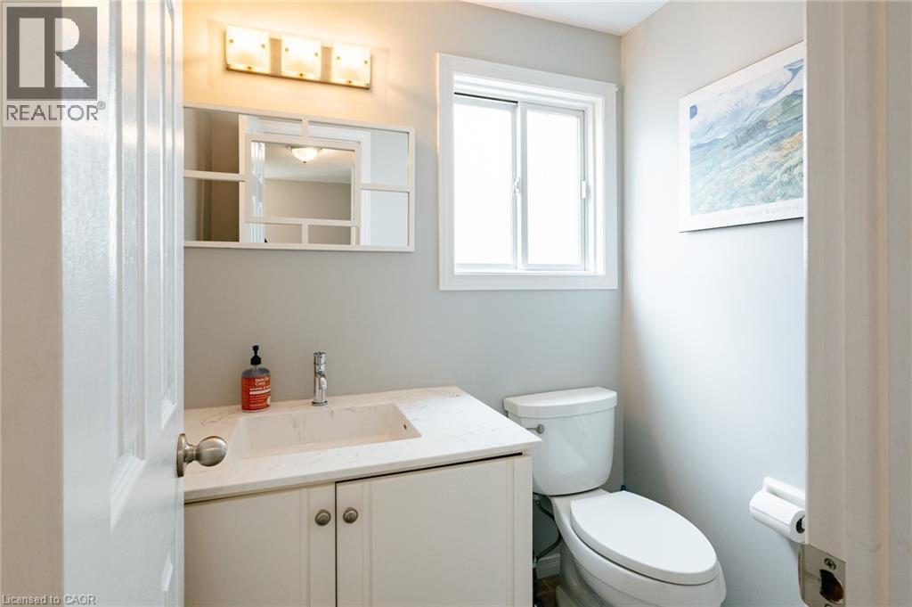 Bathroom featuring a white vanity with an integrated sink, a light-colored countertop, and a chrome faucet - 560 Penny Lane, Waterloo, ON