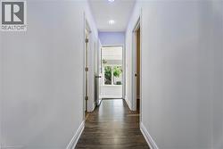 Hallway featuring wood-finish flooring, light-colored walls, recessed lighting, and white baseboards -