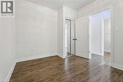 Interior room featuring wood-finish flooring, white baseboards, and neutral wall paint -