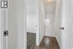 Interior hallway with wood-finish flooring, white painted walls, and white trim -
