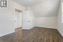 Room featuring wood-finish flooring, white baseboards, and a sloped ceiling -