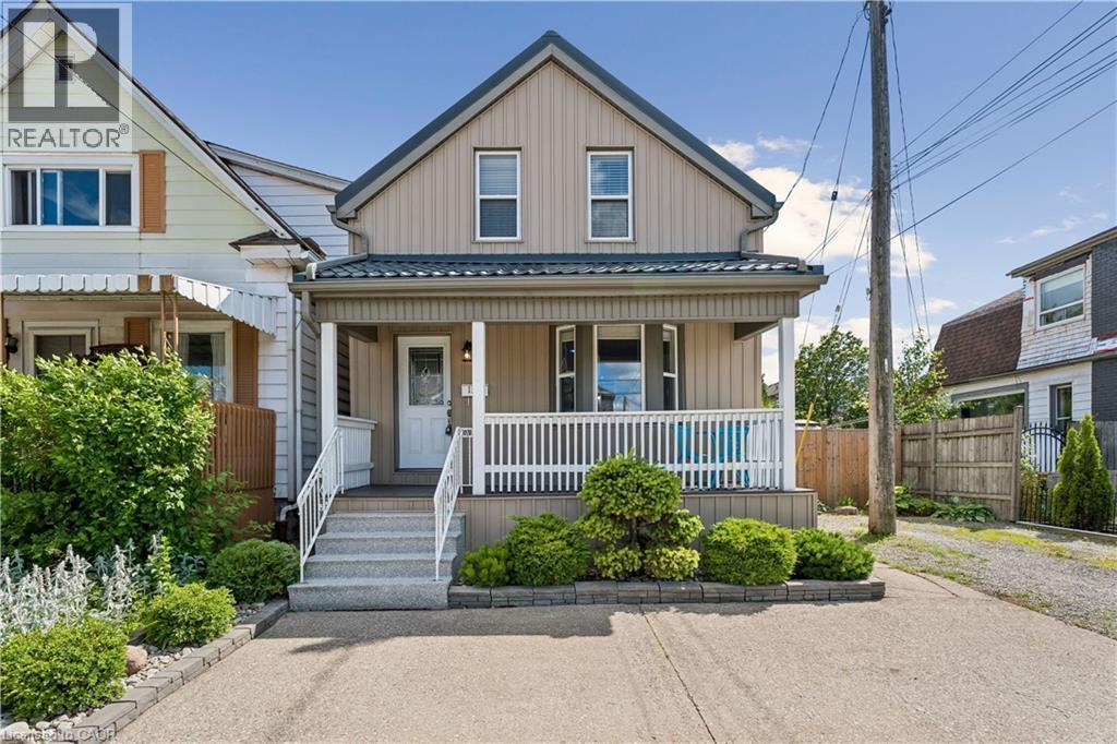 Two-story property featuring a front porch with white railing, a dormer window, and a dark metal roof - 180 Campbell Avenue, Hamilton, ON - Outdoor With Deck Patio Veranda With Facade