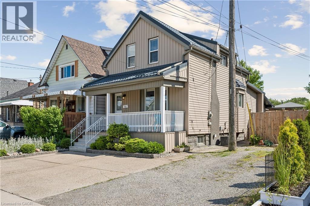 Two-story property featuring vertical siding and a covered front porch with white railings - 180 Campbell Avenue, Hamilton, ON - Outdoor With Deck Patio Veranda