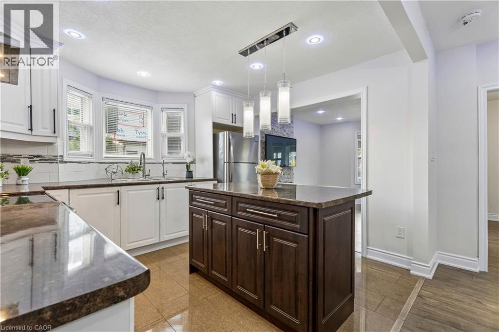 Kitchen featuring an island with a dark wood-finish cabinet base and stone-finish countertop - 180 Campbell Avenue, Hamilton, ON - Indoor Photo Showing Kitchen With Upgraded Kitchen