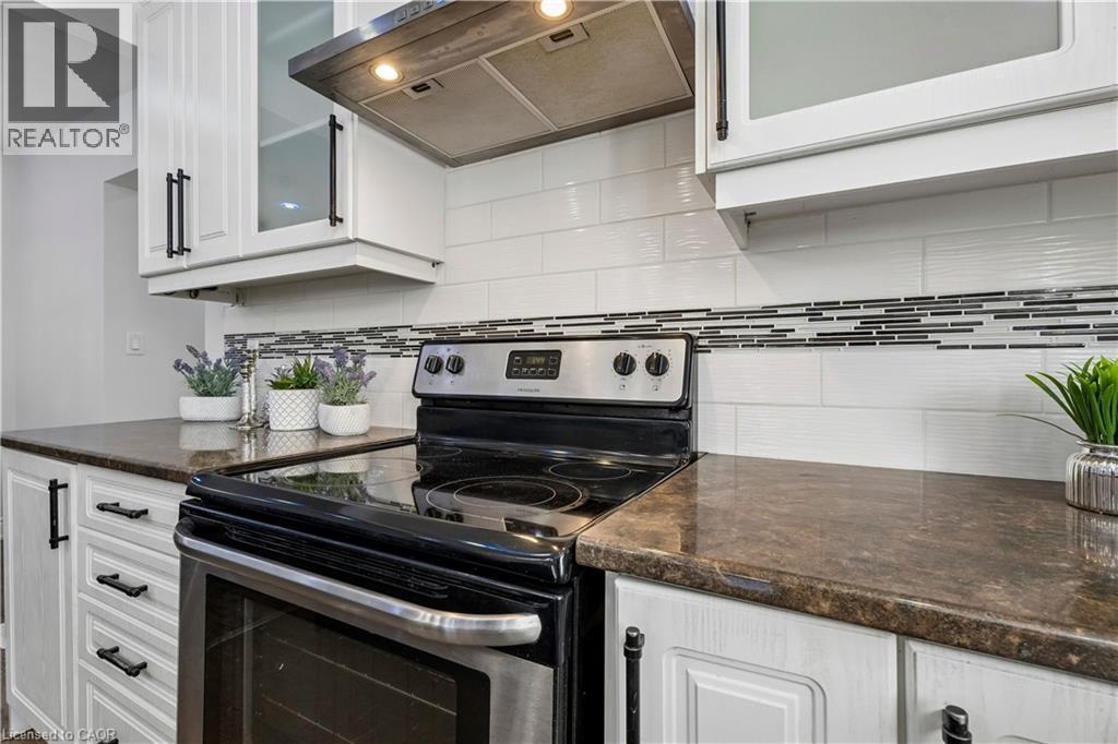 Kitchen featuring white cabinetry with dark hardware, dark countertops, and a subway tile backsplash with an accent band - 180 Campbell Avenue, Hamilton, ON - Indoor Photo Showing Kitchen With Upgraded Kitchen