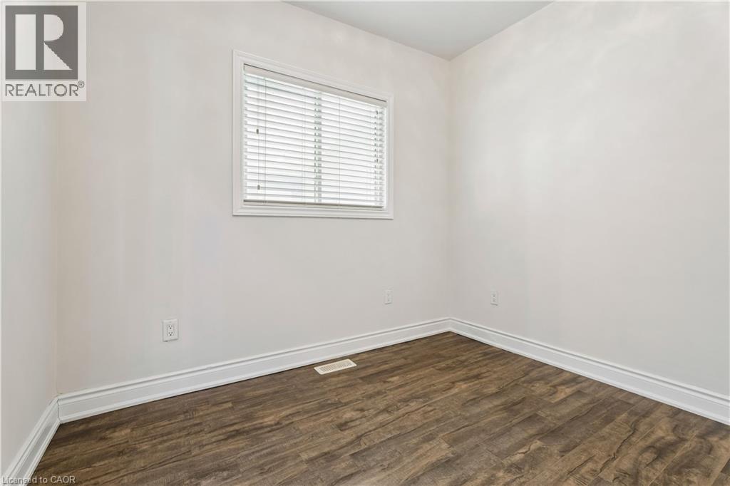 Bright interior space featuring light-toned walls, wood-finish flooring, and white baseboards - 180 Campbell Avenue, Hamilton, ON - Indoor Photo Showing Other Room
