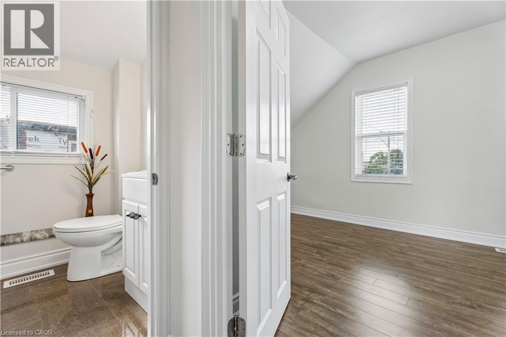 Bright interior spaces featuring a white paneled door, wood-finish flooring, and a window with blinds - 180 Campbell Avenue, Hamilton, ON - Indoor Photo Showing Bathroom