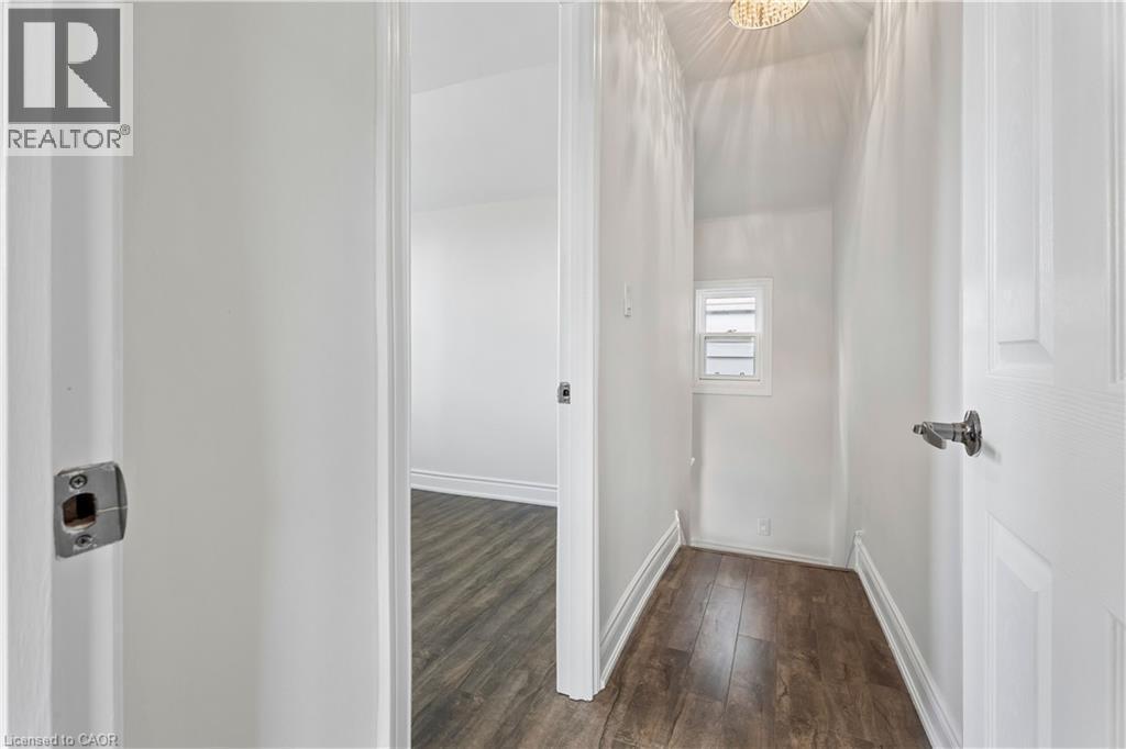 Interior hallway with wood-finish flooring, white painted walls, and white trim - 180 Campbell Avenue, Hamilton, ON - Indoor Photo Showing Other Room