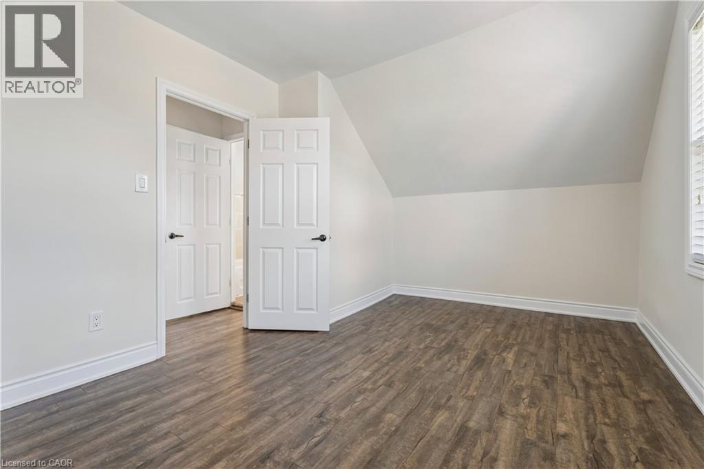 Room featuring wood-finish flooring, white baseboards, and a sloped ceiling - 180 Campbell Avenue, Hamilton, ON - Indoor Photo Showing Other Room