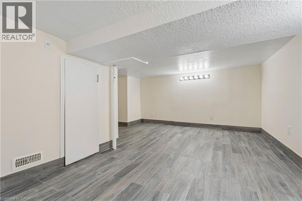 Spacious interior room featuring wood-finish tile flooring and light-toned walls - 180 Campbell Avenue, Hamilton, ON - Indoor
