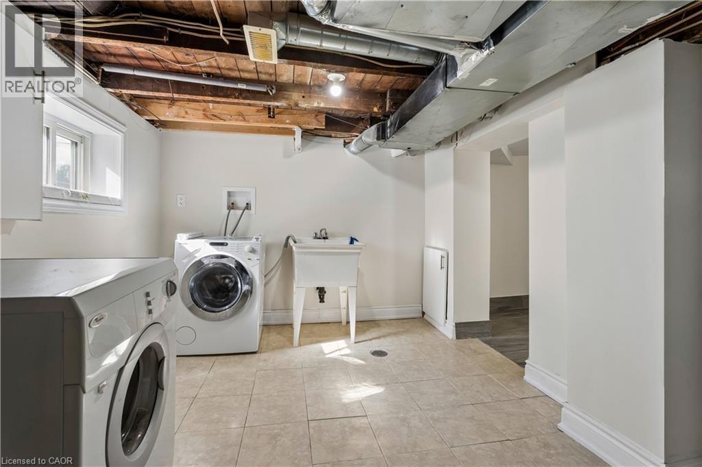 Laundry area featuring tiled flooring, a utility sink, and ample overhead ductwork - 180 Campbell Avenue, Hamilton, ON - Indoor Photo Showing Laundry Room