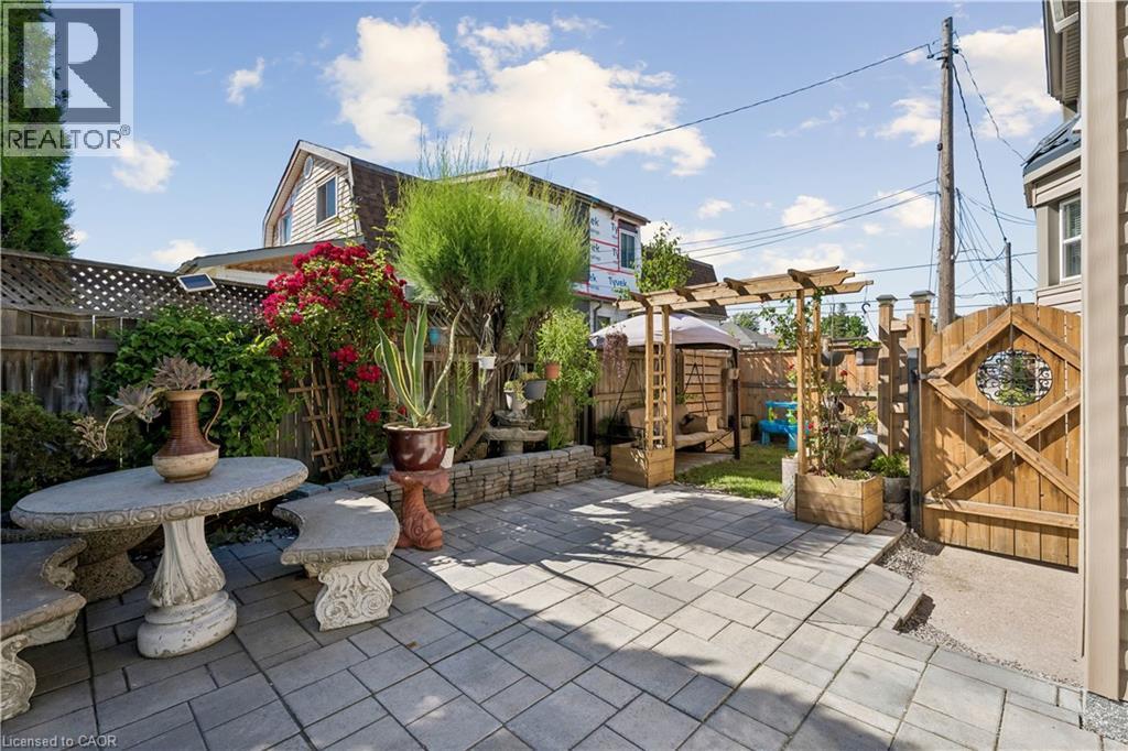 Spacious outdoor patio featuring paver stones, a wooden pergola, and a privacy fence - 180 Campbell Avenue, Hamilton, ON - Outdoor With Deck Patio Veranda