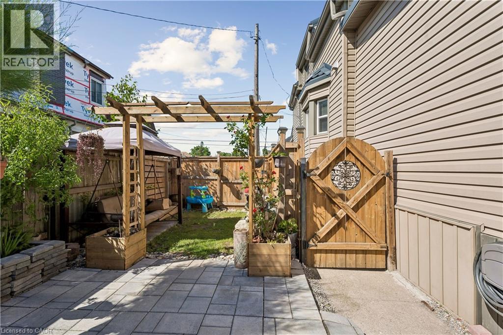 Fenced backyard featuring a paver patio, a wooden pergola, and a decorative wooden gate - 180 Campbell Avenue, Hamilton, ON - Outdoor