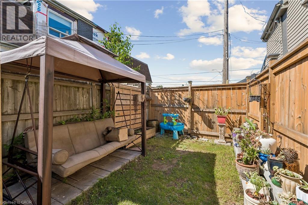 Fenced backyard featuring a grassy area, wood fencing, and a covered swing - 180 Campbell Avenue, Hamilton, ON - Outdoor