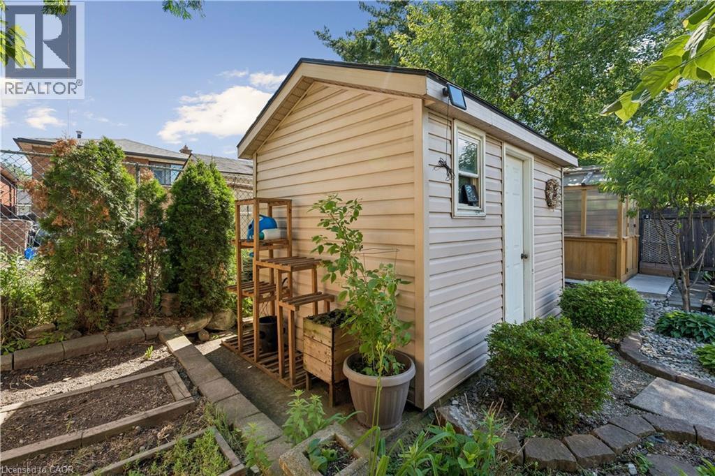 Storage shed with light beige siding and white trim, featuring a white door and small window - 180 Campbell Avenue, Hamilton, ON - Outdoor With Exterior