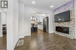 Spacious living area featuring wood-finish flooring, recessed lighting, and a modern fireplace with a stone-accented wall -