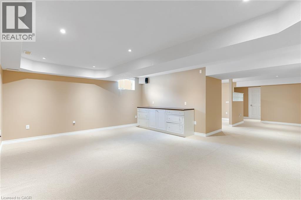 Spacious carpeted room featuring recessed lighting, a built-in white cabinet with a dark countertop, neutral wall tones, and white trim - 227 Chestnut Hill Crescent, Kitchener, ON - Indoor
